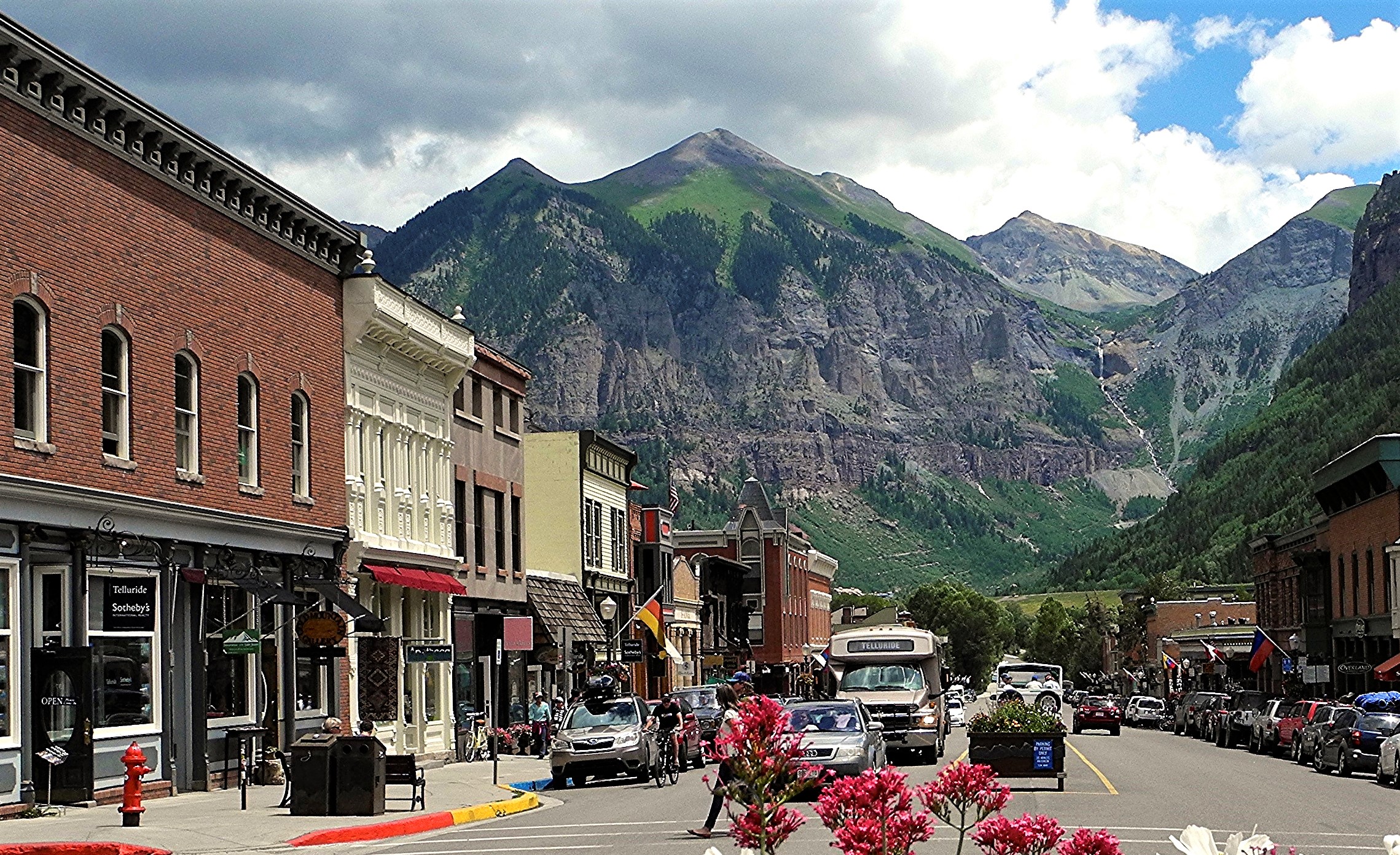 Colorful storefronts along Telluride’s Colorado Avenue, with Ajax Peak rising behind them